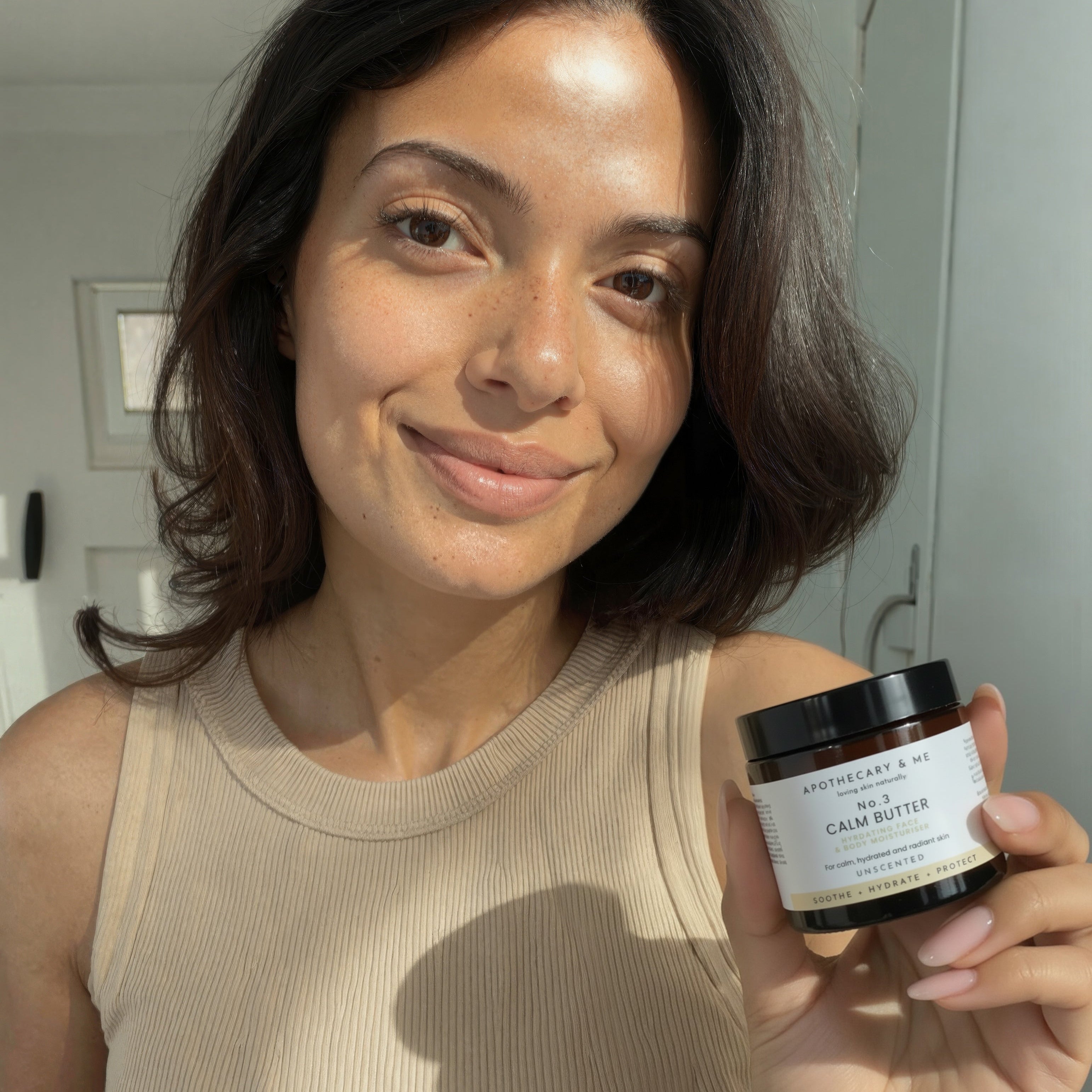 Woman holding a jar of Calm Butter in a well-lit room