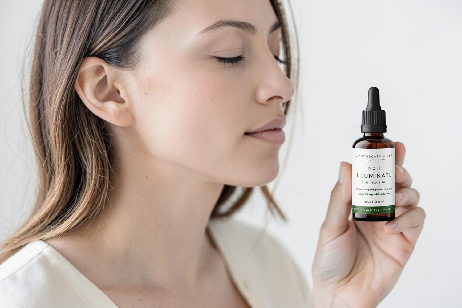 Woman with calm, clear skin holding a bottle of Apothecary & Me No.1 Illuminate Face Oil, a lightweight waterless facial oil for sensitive and reactive skin.