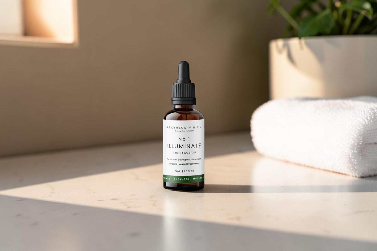 Apothecary & Me No.1 Illuminate Face Oil in warm natural light on a bathroom countertop with a folded white towel and green plant, a gentle fragrance-free face oil for naturally calming rosacea-prone skin
