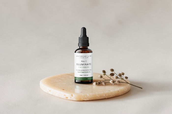 Apothecary & Me No.1 Illuminate Face Oil on a natural stone disc with a sprig of dried botanicals, a minimal three-ingredient face oil with a fully transparent INCI ingredient list